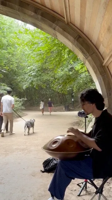Gordey playing handpan under a stone arch in Prospect Park